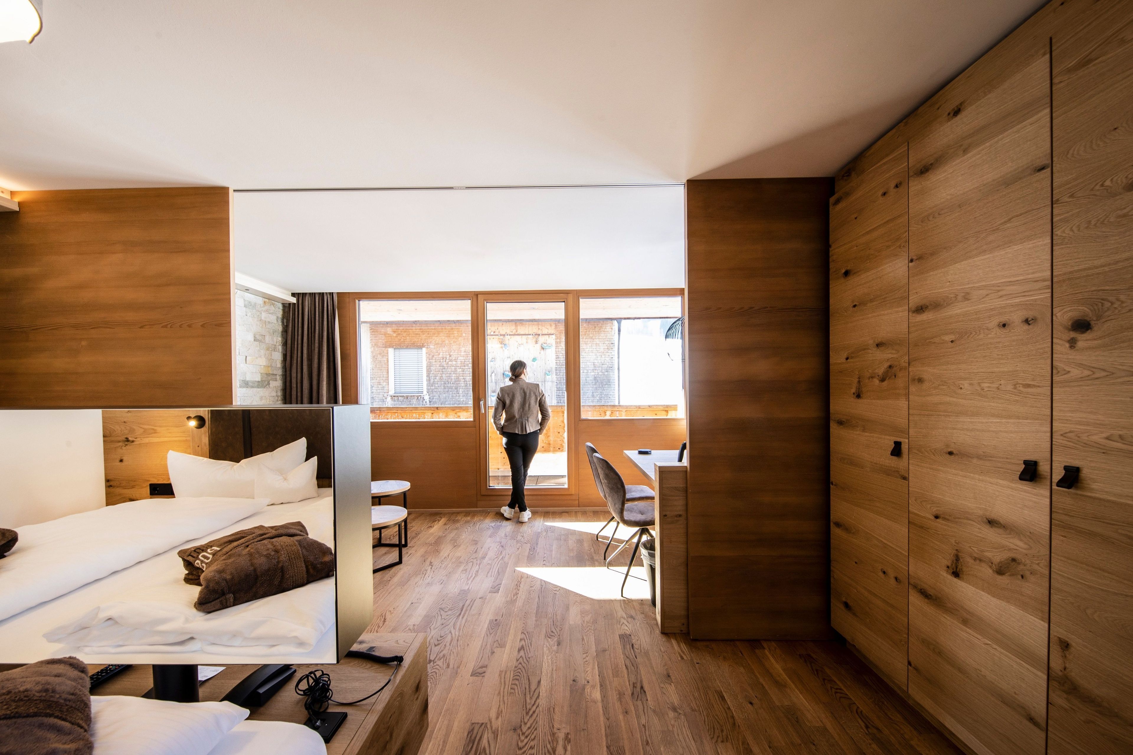 A modern hotel room with a bed, a desk, and a view of the outside.