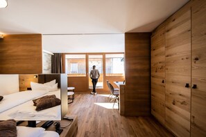 A modern hotel room with a bed, a desk, and a view of the outside.