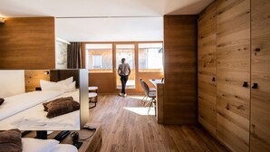 A modern hotel room with a bed, a desk, and a view of the outside.