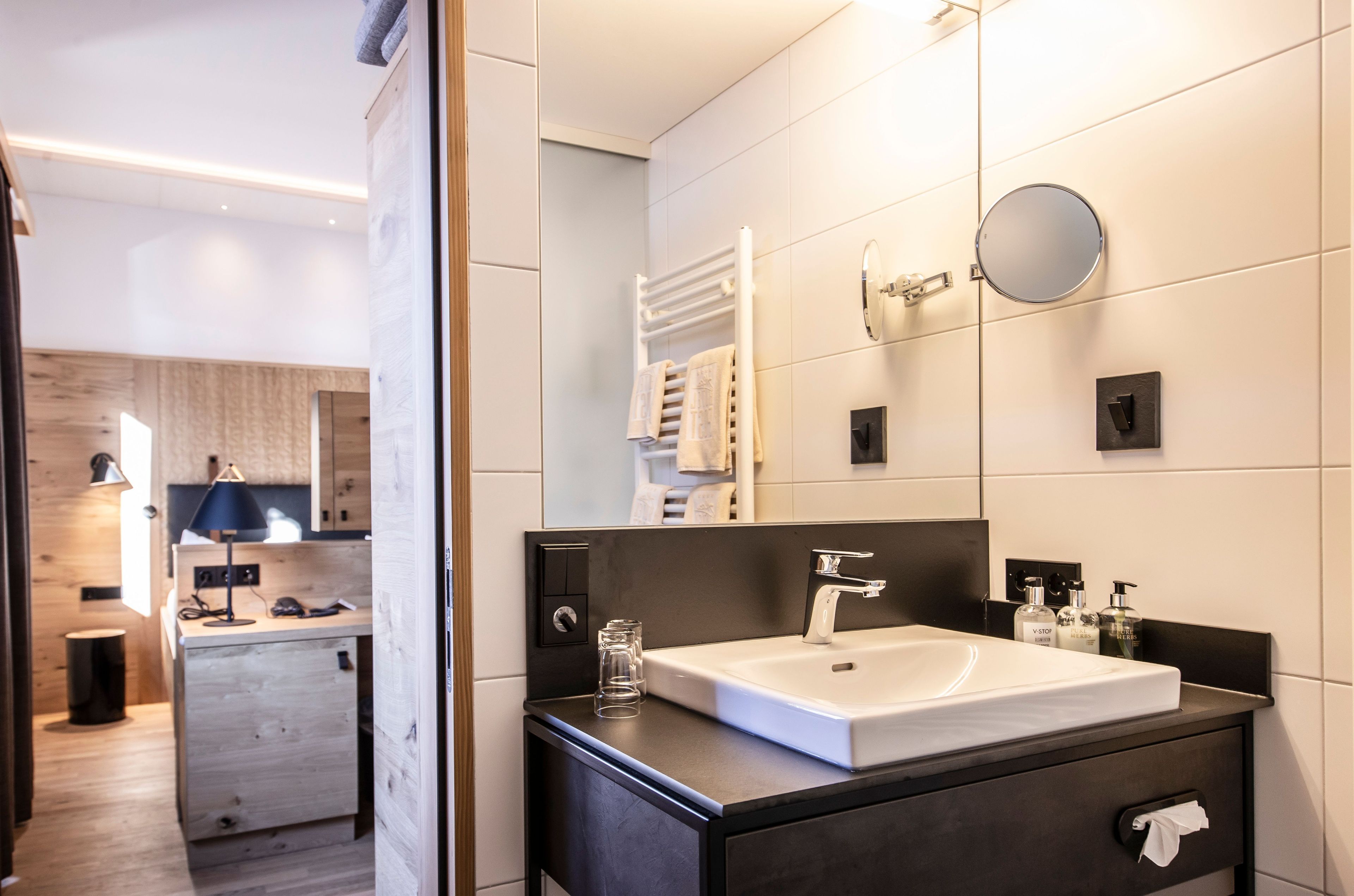 Ein modernes Badezimmer mit einem großen Waschbecken, einem Spiegel, einem Handtuchhalter und einem kleinen Glas auf der Ablagefläche.