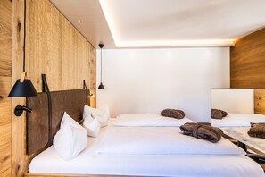 Habitación de hotel con paredes de madera, una cama con ropa de cama blanca, dos lámparas de noche y un espejo.