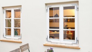 Two white-framed windows with multiple panes, each with a wooden shelf below. - Ferienwohnung Lieblingsplatz (Lueneburg)
