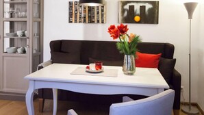 A dining area with a white table, a black sofa, and a vase with red flowers. - Ferienwohnung Lieblingsplatz (Lueneburg)