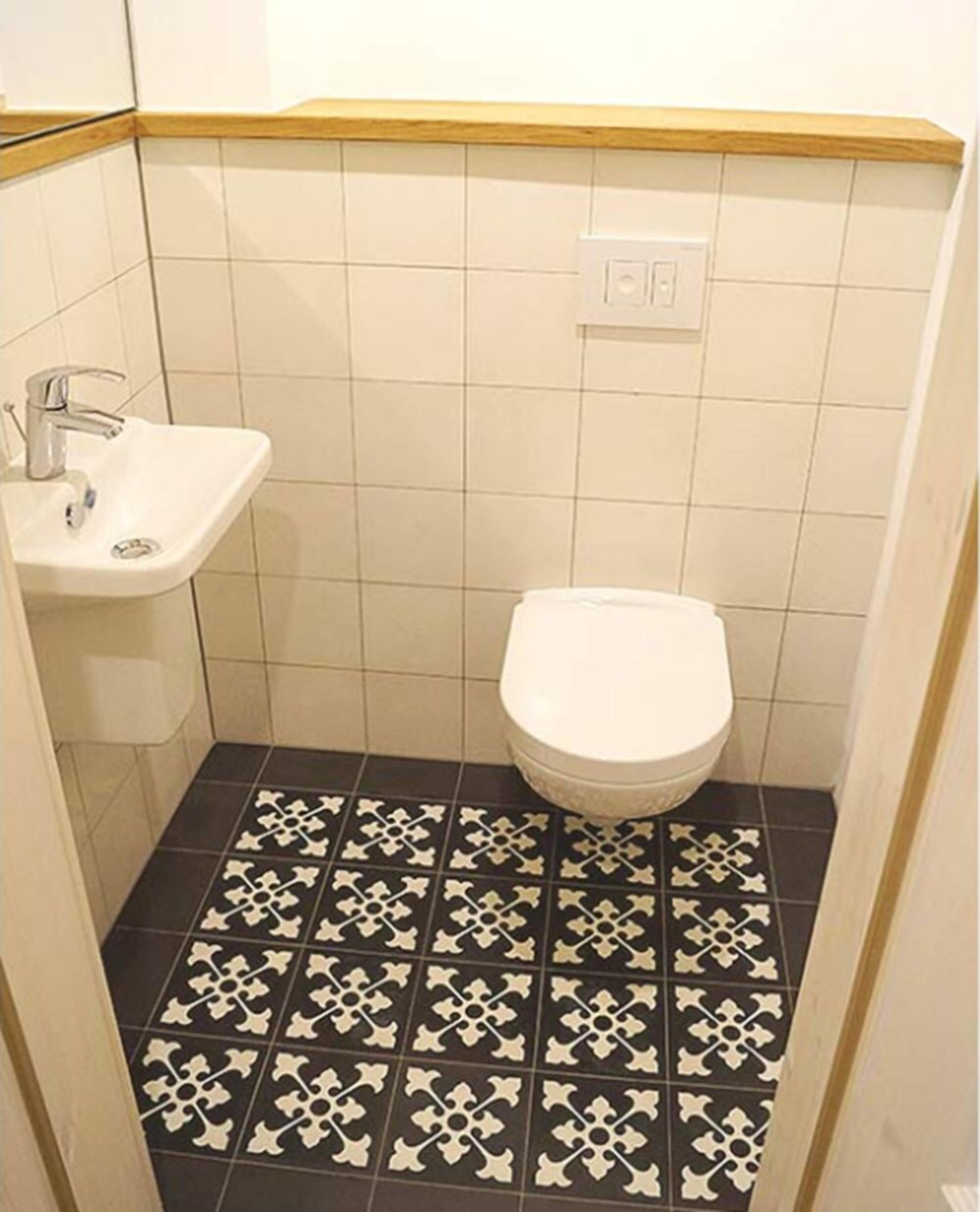 A small bathroom with a white sink, toilet, and black and white patterned floor tiles.