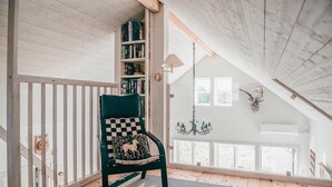 A cozy reading nook with a wooden chair, a bookshelf, and a chandelier. - Cozy home in Södra Vi with sauna (Södra Vi)