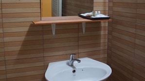 Un baño con un lavabo blanco, un espejo y una repisa encima.