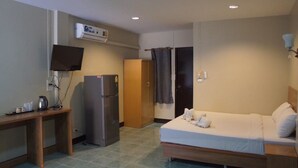 Habitación de hotel con cama, escritorio, refrigerador, televisor y armario.