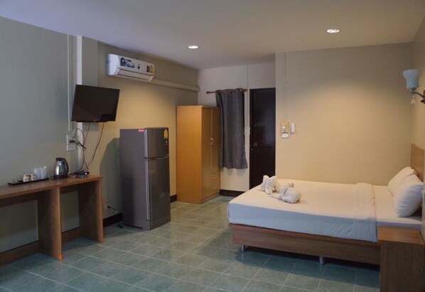A hotel room with a bed, a desk, a refrigerator, a television, and a wardrobe. - Huan Kham Nan (Nan)