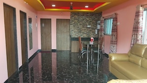 Una sala de estar moderna con piso de mármol negro, un sofá, una zona de comedor con una mesa y sillas, y una cocina con salpicadero de piedra.