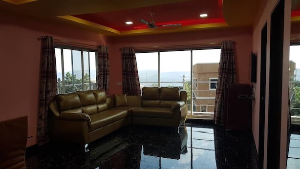 Una sala de estar con sofá, ventanas amplias y ventilador de techo.