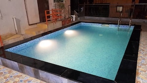 Una piscina rectangular con suelo de baldosas y borde negro.