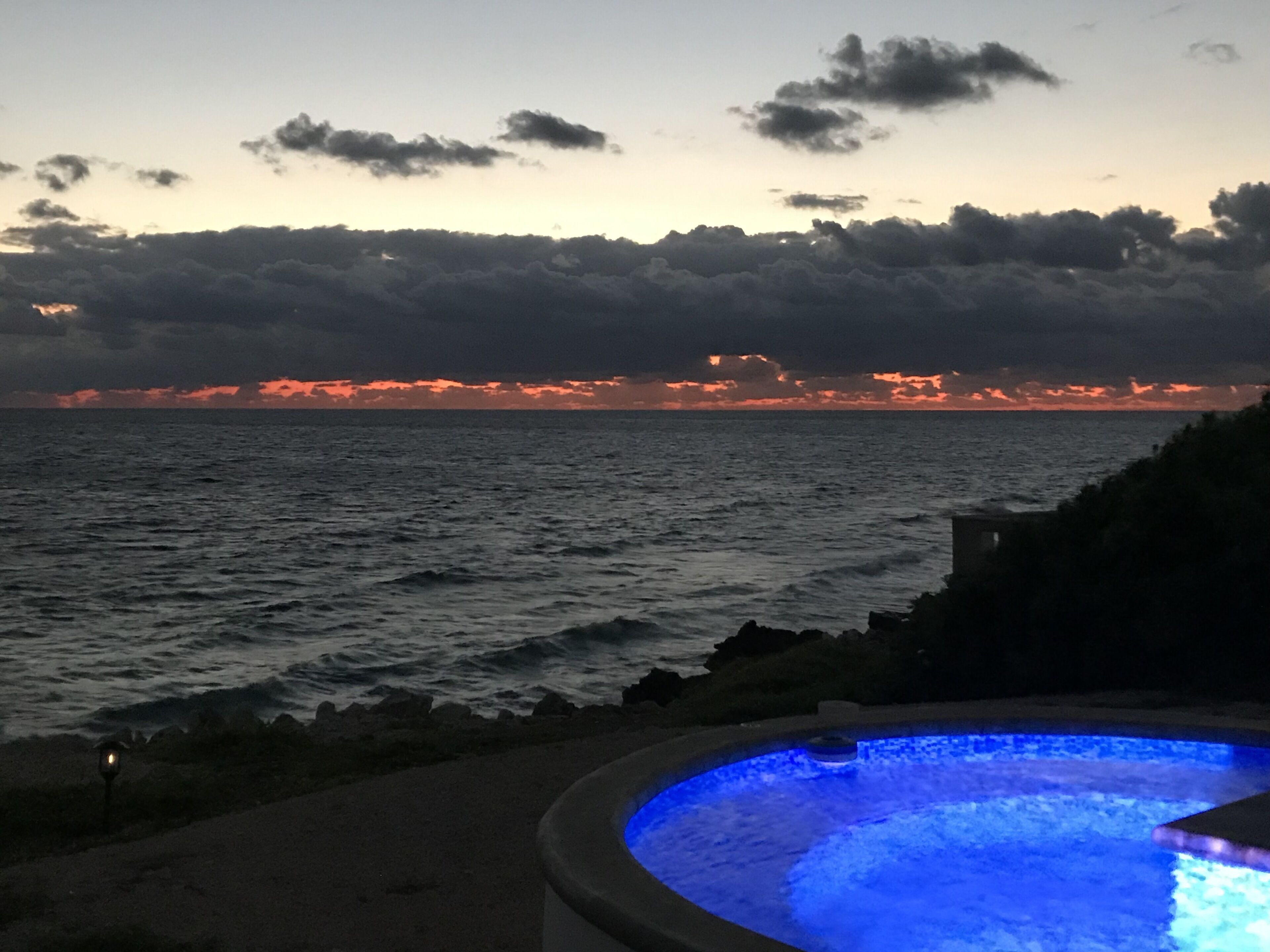 Ein Pool mit Blick auf das Meer und einen Sonnenuntergang.