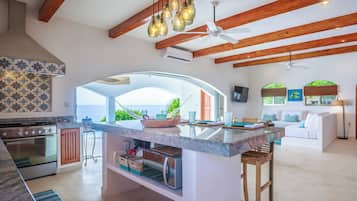 A spacious kitchen with a large island, wooden beams, and a view to the outdoors.