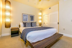 A bedroom with a bed, bedside tables, a wooden bench, and wall-mounted lighting fixtures.