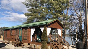A rustic cabin with a green roof, wooden exterior, and a small porch area.