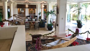A spacious lobby with a central seating area, a decorative boat, and a staircase leading to upper floors. - Deluxe Room w/King Bd, Ocean/Pool views, New Furnishings!, No Resort Fee (Lihue)