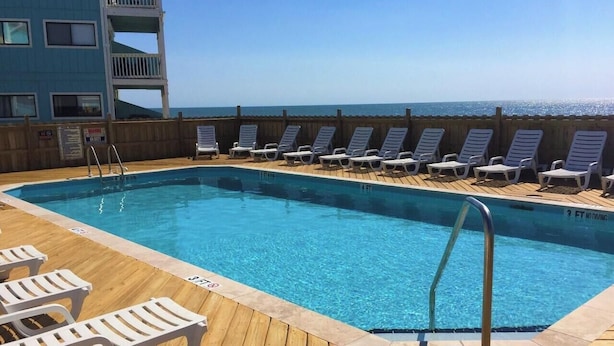 A pool area with lounge chairs and a wooden deck. - Pleasure Island Paradise - closest rental to the beach you will find (Kure Beach)