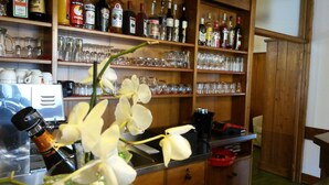 Eine Bar mit Flaschenregalen voller Spirituosen und Gläsern, einer Kaffeemaschine und einer Blumenkomposition.