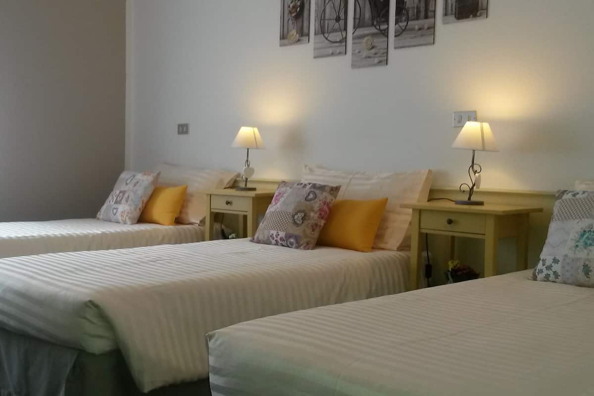 Una habitación de hotel con dos camas individuales, cada una con una almohada y una mesita de noche con lámpara.