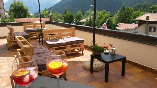 Eine Terrasse mit Holzmöbeln, darunter eine Couch und ein Tisch mit Getränken und Blumen.