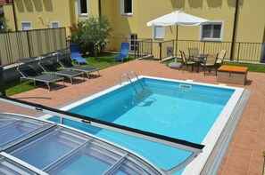 Una piscina al aire libre de temporada, sombrillas