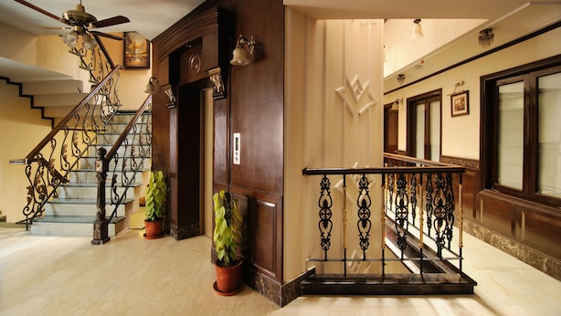 A grand staircase with ornate metal railings and a ceiling fan. - Hotel Diplomat Residency (New Delhi)