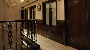 A hotel lobby with a marble floor, a staircase with ornate black railings, and a dark wooden door with the number 204. - Hotel Diplomat Residency (New Delhi)