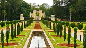 Un jardín formal con una fuente central, senderos simétricos y un arco de entrada destacado.