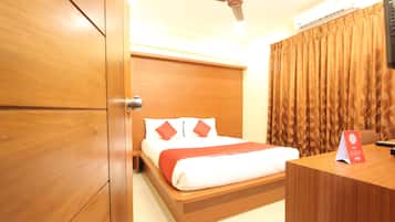 A hotel room with a wooden bed, a desk, a ceiling fan, and a window with curtains.