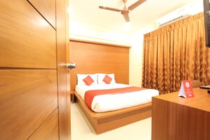 A hotel room with a wooden bed, a desk, a ceiling fan, and a window with curtains.