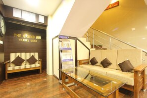 Una zona de recepción de viajes con un banco de madera, una mesa de cristal y un sofá con cojines marrones.