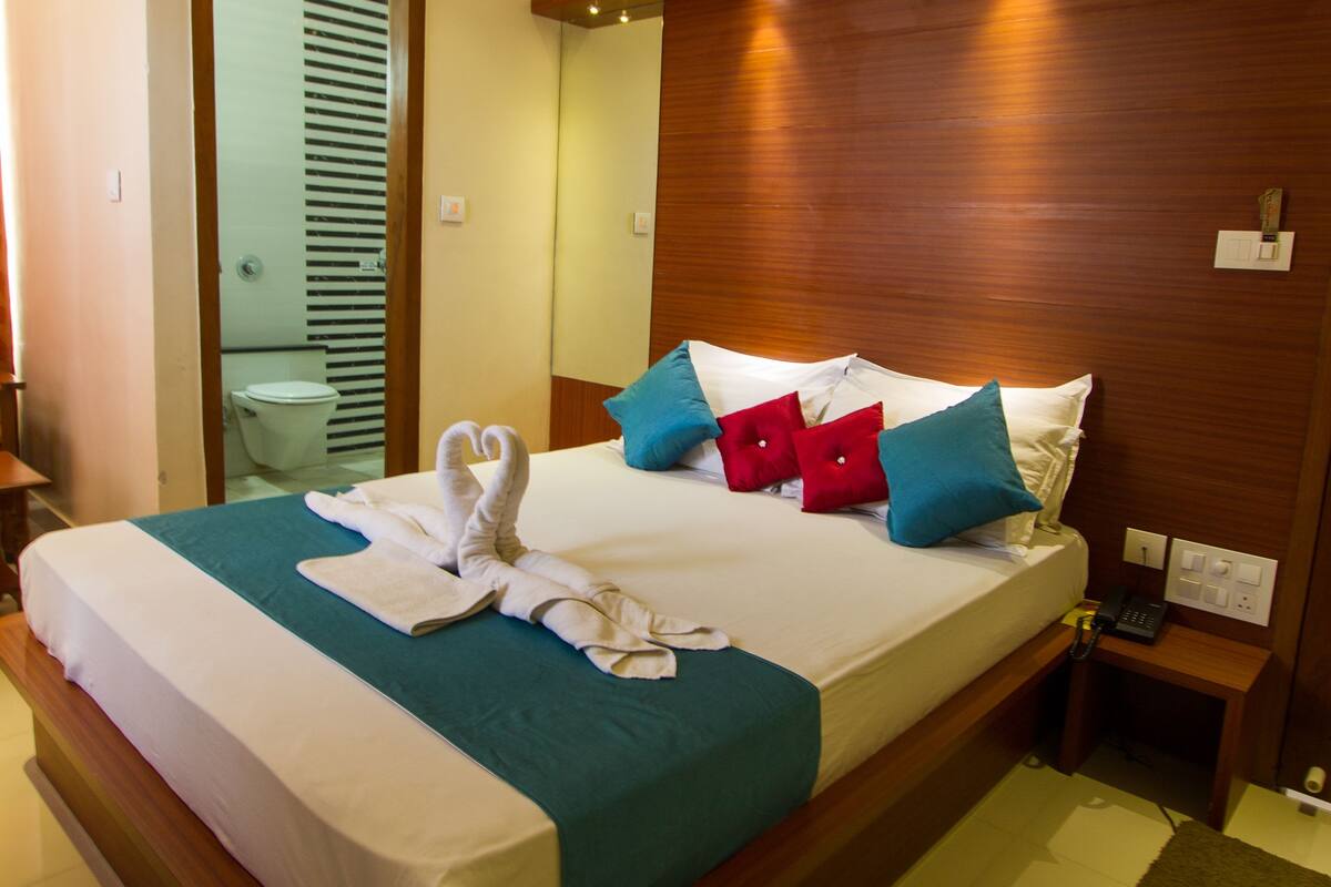 A neatly made bed with a blue and white bedspread, a wooden headboard, and a small bedside table with a lamp.