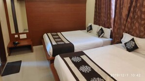 Habitación de hotel con dos camas, cabecero de madera, mesita de noche, espejo y ventana con cortinas.