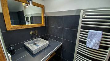 A bathroom with a wooden-framed mirror, a vessel sink, and a towel rack with a towel.