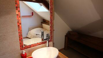 A bathroom with a white sink, red soap dispenser, and a mirror with a red frame.