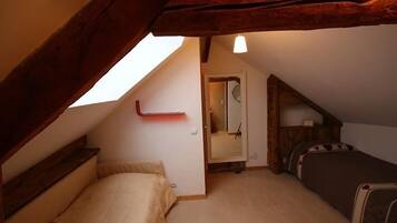 A small, cozy attic bedroom with a sloped ceiling, a single bed, and a small table.