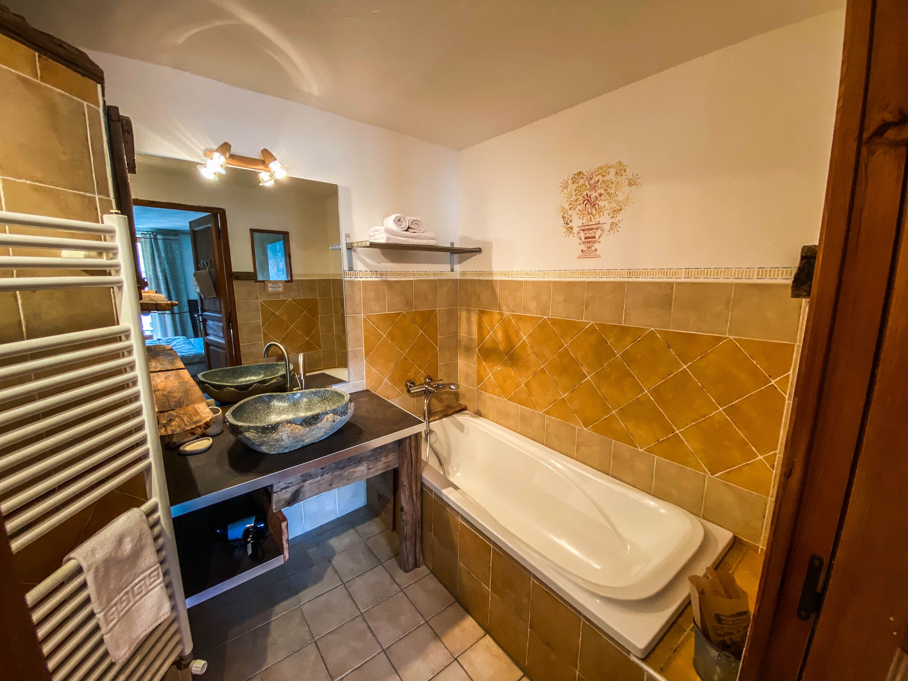 Een badkamer met een bad, twee wastafels en een spiegel.