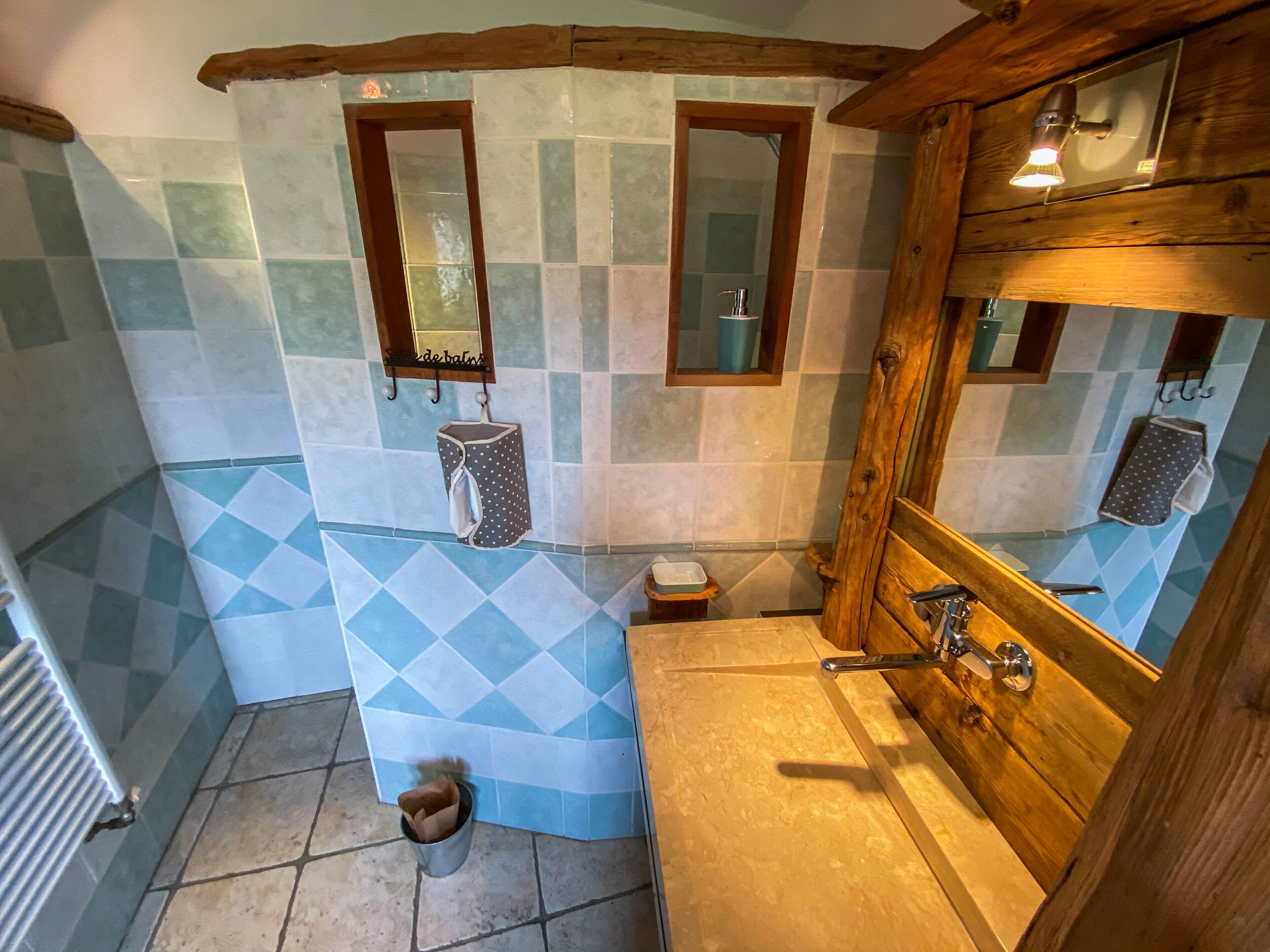 Une salle de bain avec un meuble-lavabo en bois, un miroir et un mur recouvert de carreaux disposés en motif losange.