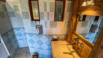 Une salle de bain avec un meuble-lavabo en bois, un miroir et un mur recouvert de carreaux disposés en motif losange.