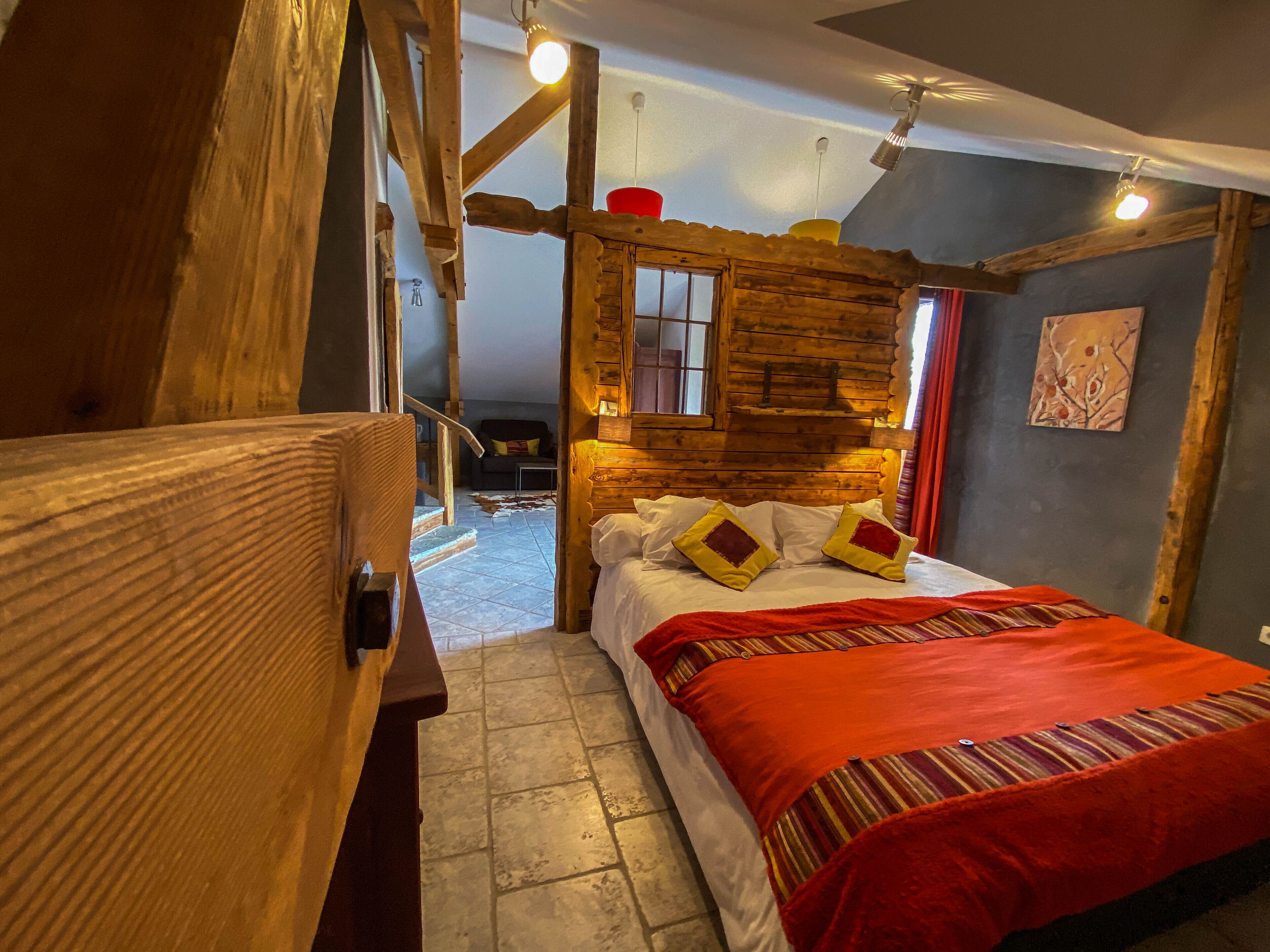 Un dormitorio estilo cabaña de madera acogedor, con cama, almohadas y una manta roja.