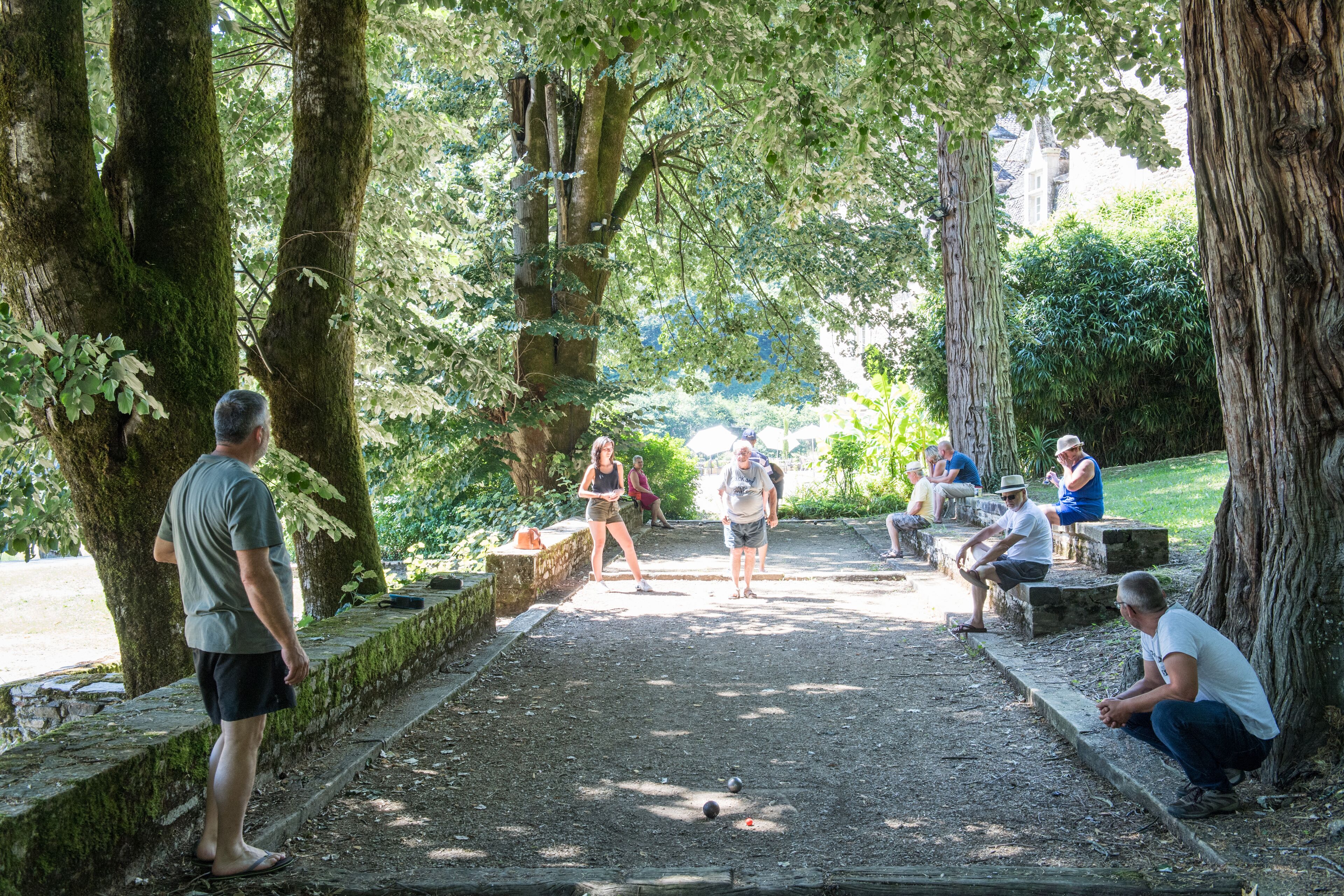 A park with a dirt path, benches, and people.