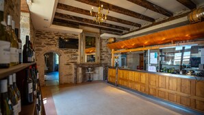 A bar area with wooden paneling, a stone wall, and a chandelier. - Camping le Gibanel (Saint Martial Entraygues)
