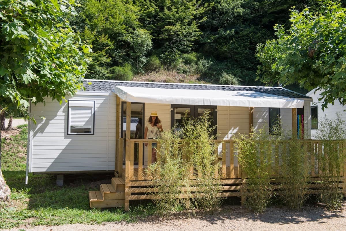 Ein kleines, eingeschossiges Mobilheim mit überdachter Veranda und Eingangstür.