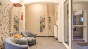 Un pasillo con una pared curva, un mostrador de recepción y una zona de estar con dos sillones.
