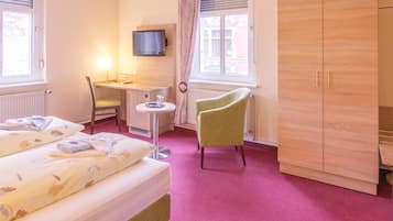 A hotel room with two beds, a desk with a chair, a television, and a wardrobe.