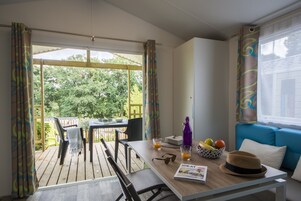 Una habitación con una mesa de madera, sillas, un sofá y una ventana con cortinas.