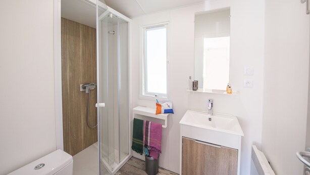 Un baño moderno con cabina de ducha de vidrio, un lavamanos blanco y un espejo encima.