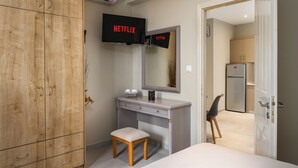 A bedroom with a wooden wardrobe, a vanity with a mirror, a small stool, and a television displaying 'NETFLIX' and 'X-FILM'. - Villa Liostasi (Corfu)
