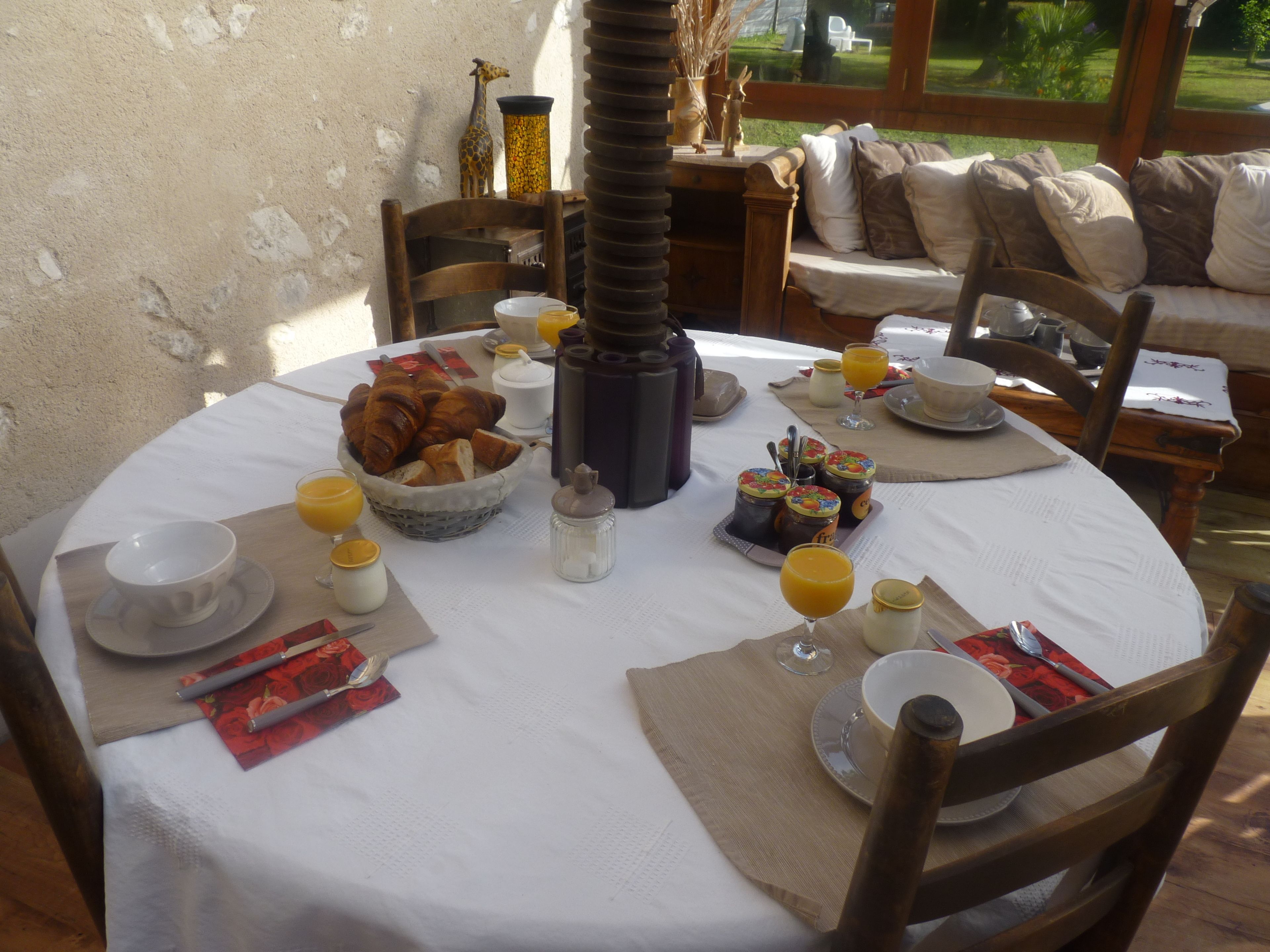 A breakfast table set with croissants, bread, and fruit.