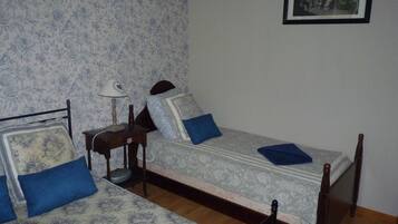 A bedroom with two single beds, a nightstand with a lamp, and a framed picture on the wall.